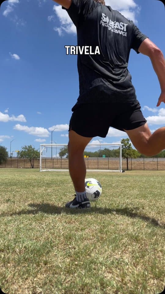 A player striking a soccer ball with the outside of the foot